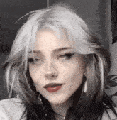 a girl with white hair and black hair is wearing a nose ring and red lipstick .