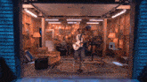 a woman is singing into a microphone while playing a guitar in a garage