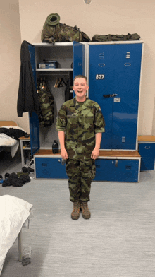 a man in a military uniform is standing in front of lockers with the number b27 on them