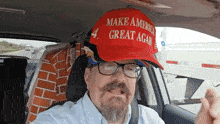 a man wearing a make america great again hat is sitting in a car