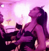 a woman in a black dress is being brushed by another woman in a purple room