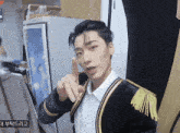 a man in a black and gold jacket is pointing his finger up