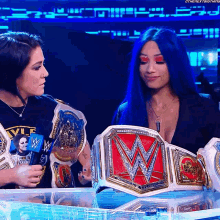 a woman with blue hair holds a wrestling championship belt