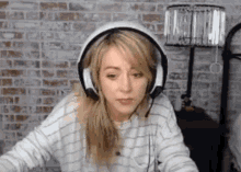a woman is wearing headphones and looking at the camera .