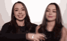 a couple of women standing next to each other with a question mark on their hands .