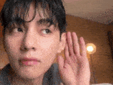 a close up of a young man 's face with his hand covering his ear .