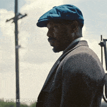 a man wearing a blue hat and a suit has #sinnersmovie written in the corner