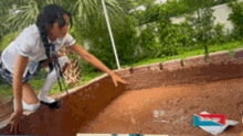 a girl in a school uniform is reaching into a pool of dirt