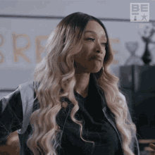 a woman with long blonde hair is wearing a black jacket