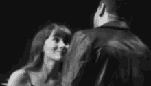 a man and a woman are kissing in a black and white photo . the woman is wearing a leather jacket .