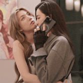 two women are hugging each other and one is holding a phone in her hand