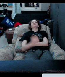 a man in a black shirt is sitting in a chair with his hands on his knees