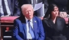 a man in a blue suit and tie is sitting next to a woman in a black suit .