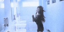 a woman is dancing in a bathroom with her hair blowing in the wind