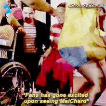 a woman in a yellow shirt is dancing in front of a man in a wheelchair who says fans has gone excited