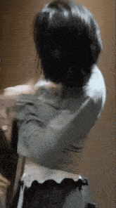 a woman is standing in a room with her arms outstretched and taking off her shirt .