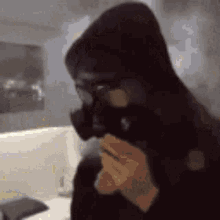 a person wearing a gas mask and a hood is blowing smoke out of their mouth .