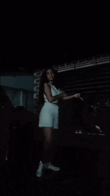 a woman is standing in front of a garage door holding a firework .