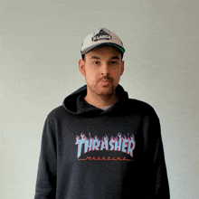 a man wearing a thrasher hoodie and a hat