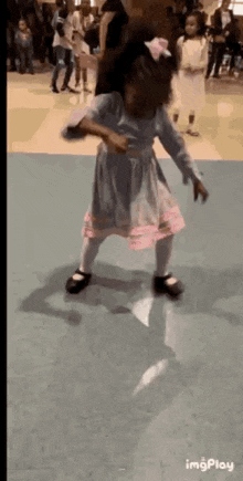 a little girl in a dress is dancing on a blue floor .