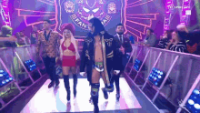 a wrestler is walking down a ramp with a woman in a red bikini .