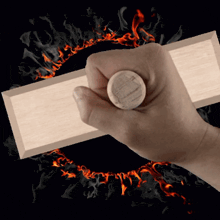 a hand holding a piece of wood with a circle around it