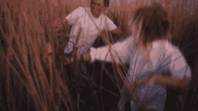 a man and a woman are standing in a field of tall grass .