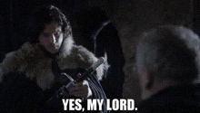 a woman in a fur coat is holding a sword and talking to a man in a dark room .