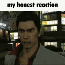 a man in a suit and red shirt is making a funny face in front of a sign that says `` my honest reaction '' .