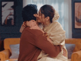 a man and woman kissing in a living room with a picture on the wall behind them