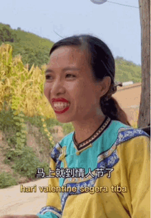 a woman wearing a blue and yellow shirt is smiling and the words hari valentine segera tiba are below her