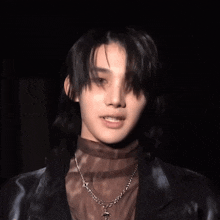 a close up of a person wearing a necklace with a cross on it