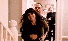 a man is carrying a woman on his back in a hallway .
