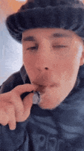 a man wearing a black hat is smoking a joint