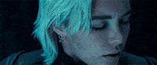 a close up of a person 's face with blue hair and piercings .