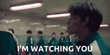 a man in a green shirt says i 'm watching you in front of a group of people