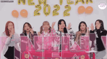 a group of girls are sitting around a table with balloons that say 2022 on them