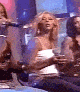 a woman in a white tank top is holding a microphone in her hand