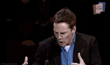 a man giving a speech in front of a sign that says " letters live "