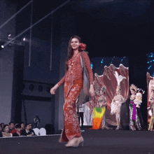 a woman in a red dress walks down the runway at a fashion show