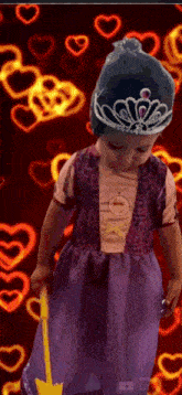 a little girl dressed as rapunzel is holding a guitar and wearing a tiara