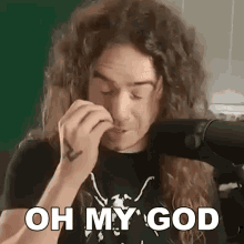 a man with long curly hair is blow drying his hair and says " oh my god "