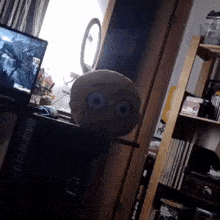 a pillow with a face on it is sitting in front of a computer screen .