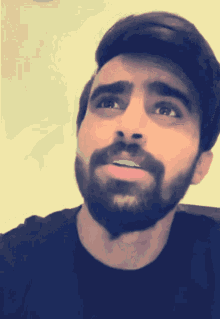 a man with a beard wearing a black shirt looks up