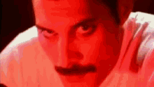 a close up of a man 's face with a mustache and a red background .