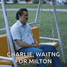 a man with a mustache is sitting on a swing with the words charlie waiting for milton written on it .