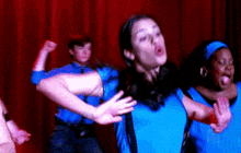 a group of people in blue shirts are dancing on a stage