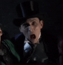 a man in a top hat and tie is screaming at another man