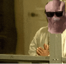 a person wearing sunglasses and a pink mask is behind a fence