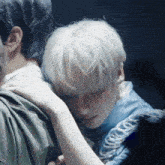 a man with white hair is hugging another man in a blue shirt